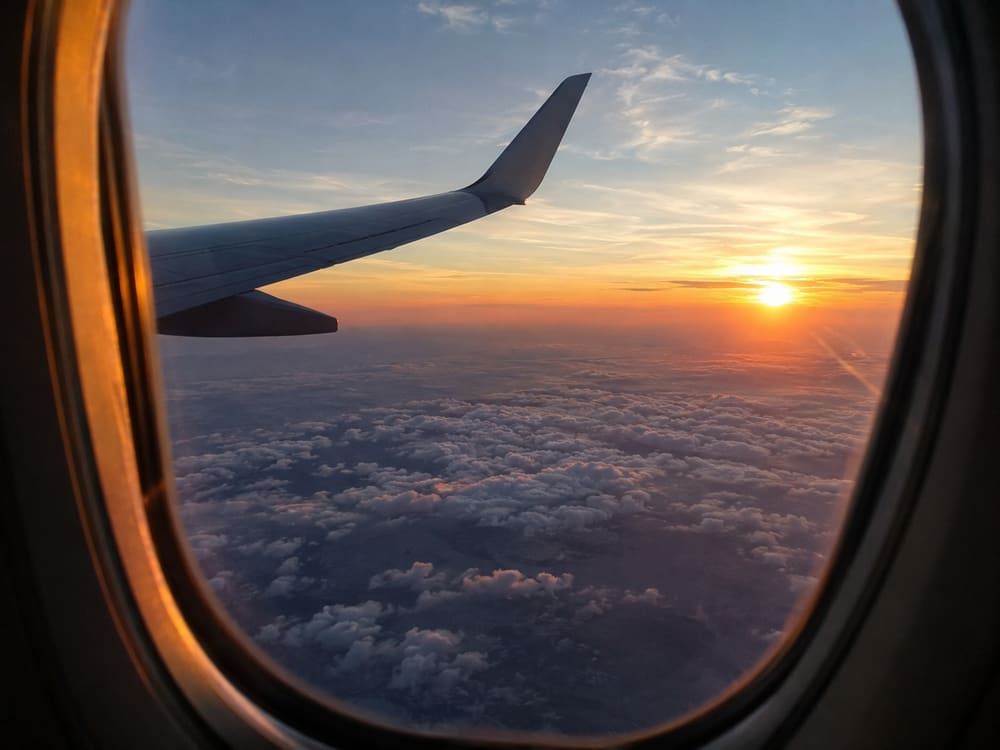 Vista del ala de un avión sobre las nubes al atardecer